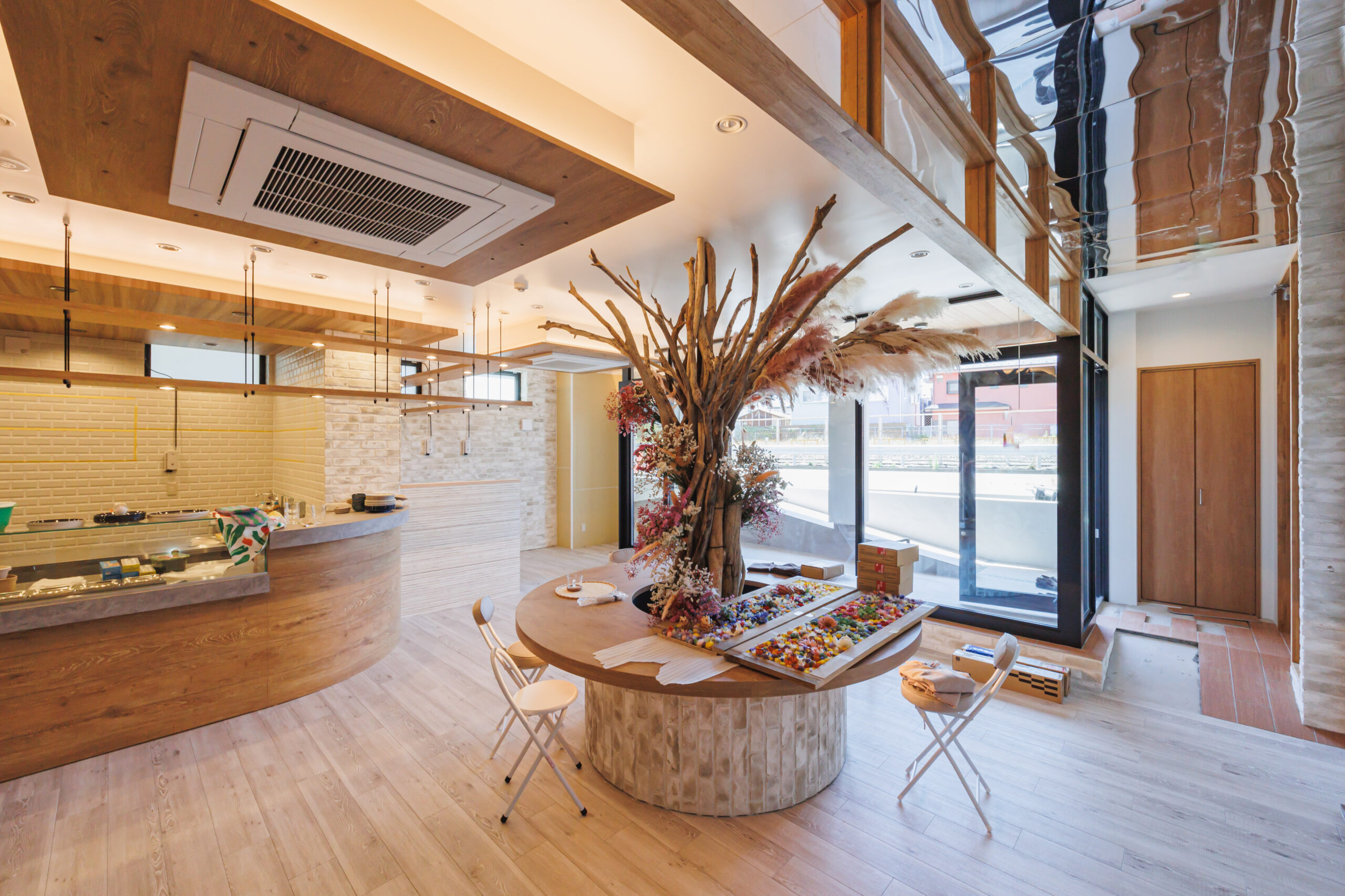 The interior of the commercial area has a foyer also covered in wooden materials and accents. From the reception desk, circular welcome table, floors, doors and even accent panels surrounding the h-vac on the ceiling.