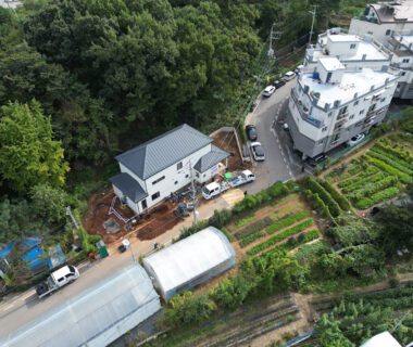 Aerial view of a mid-rise residential building across the street from a large, detached home under construction.