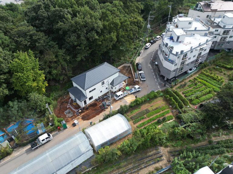 Aerial view of a mid-rise residential building across the street from a large, detached home under construction.