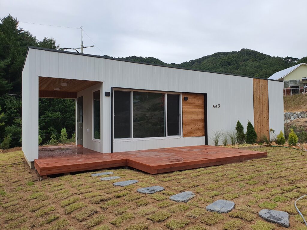 Closer look at a small home with wood accents, including a large deck that is partially covered.